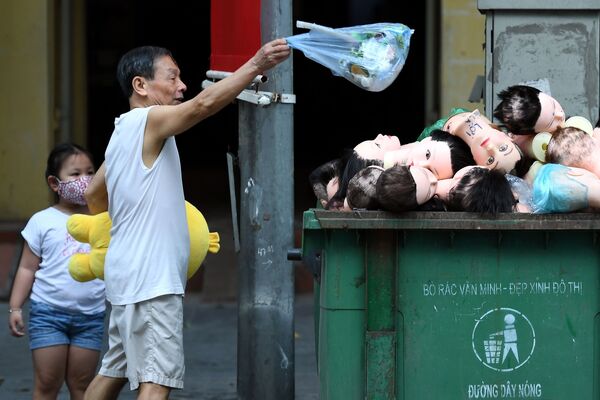 Người đàn ông vứt túi rác vào thùng đựng đầy đầu ma nơ canh ở Hà Nội, Việt Nam.
 - Sputnik Việt Nam