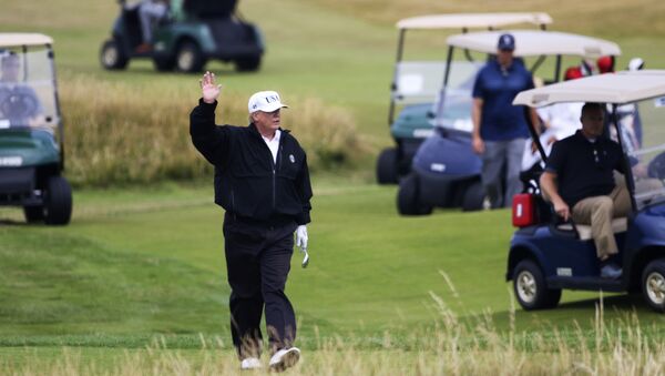 Tổng thống Mỹ Donald Trump vẫy tay chào người biểu tình khi chơi golf tại câu lạc bộ golf Turnberry, ở Turnberry, Scotland, Thứ Bảy, ngày 14 tháng 7 năm 2018. Một chục người biểu tình đã tổ chức một buổi dã ngoại phản đối trên bãi biển trước khu nghỉ mát chơi gôn Trump Turnberry ở Scotland, nơi Tổng thống Donald Trump đang dành cuối tuần với đệ nhất phu nhân. - Sputnik Việt Nam