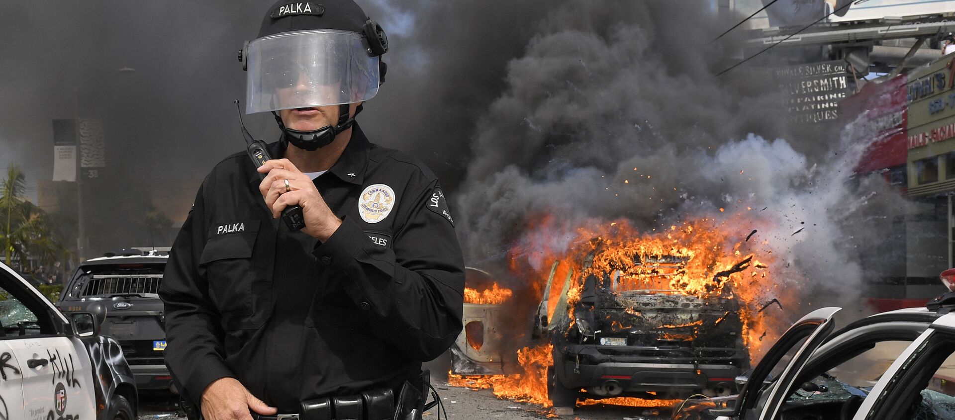 Cảnh sát Los Angeles trên nền chiếc xe bị đốt cháy trong cuộc biểu tình - Sputnik Việt Nam, 1920, 08.06.2020