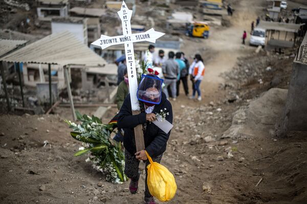 Người thân của một nạn nhân coronavirus mang thánh giá trên một nghĩa trang ở ngoại ô Lima, Peru - Sputnik Việt Nam