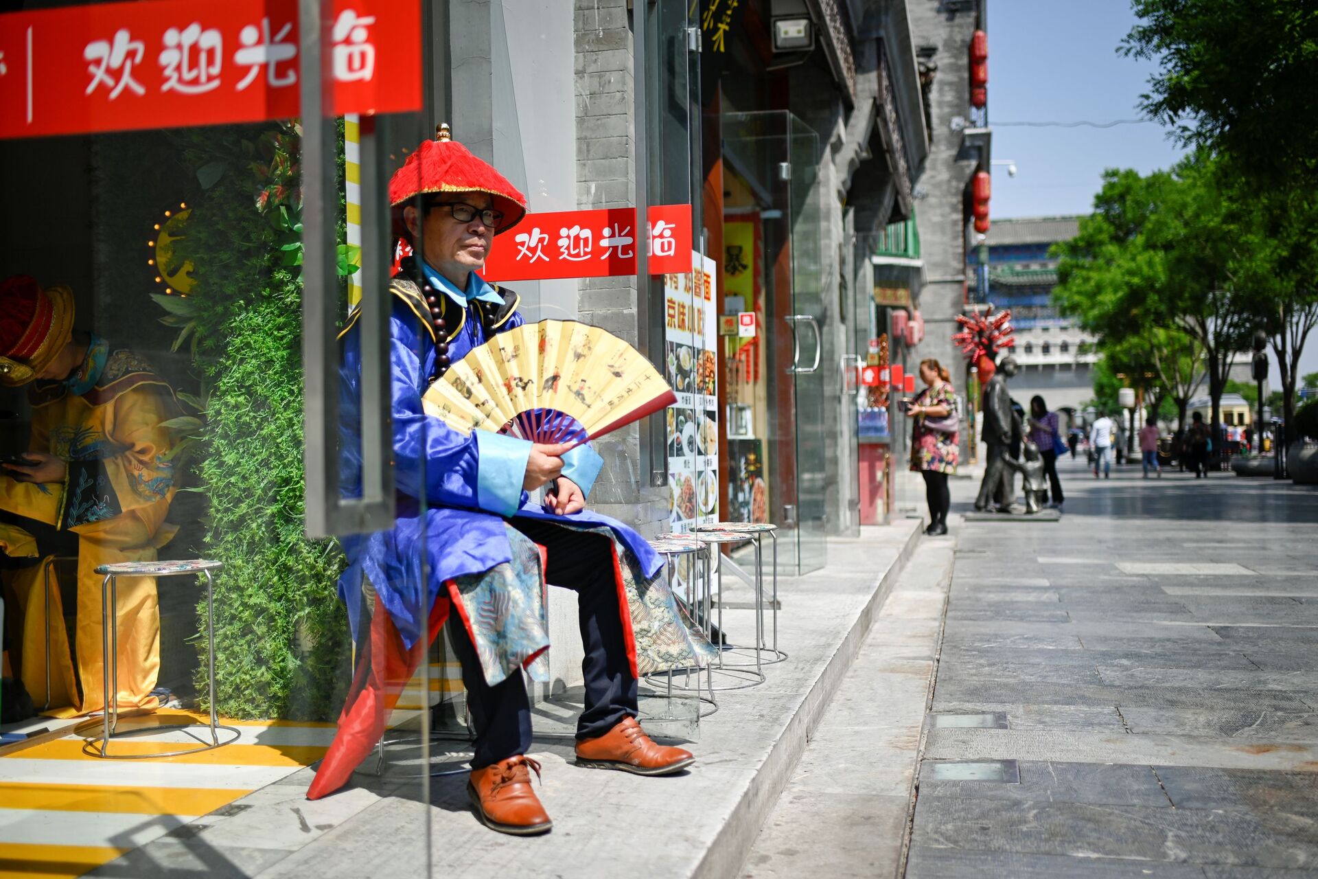 Người bán hàng bên lối vào một cửa hàng trên một con phố ở Bắc Kinh, Trung Quốc - Sputnik Việt Nam, 1920, 05.10.2021