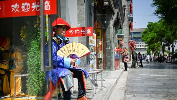 Người bán hàng bên lối vào một cửa hàng trên một con phố ở Bắc Kinh, Trung Quốc - Sputnik Việt Nam