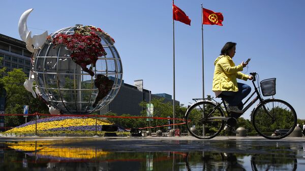 Một người phụ nữ đi xe đạp ở quảng trường trước một ngân hàng ở Bắc Kinh. - Sputnik Việt Nam