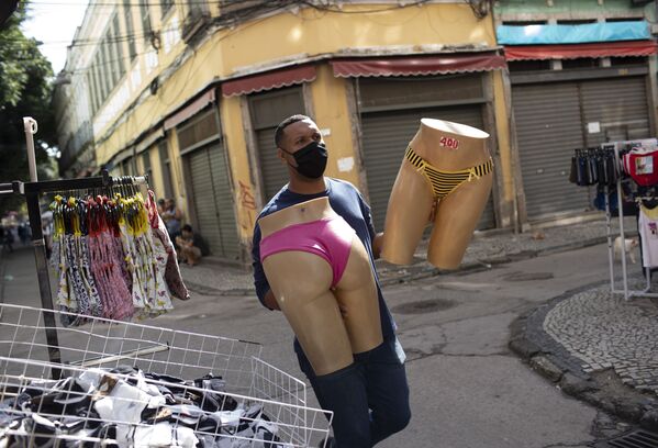 Người bán hàng đeo khẩu trang di chuyển ma-nơ-canh tại khu chợ đường phố Rio de Janeiro - Sputnik Việt Nam
